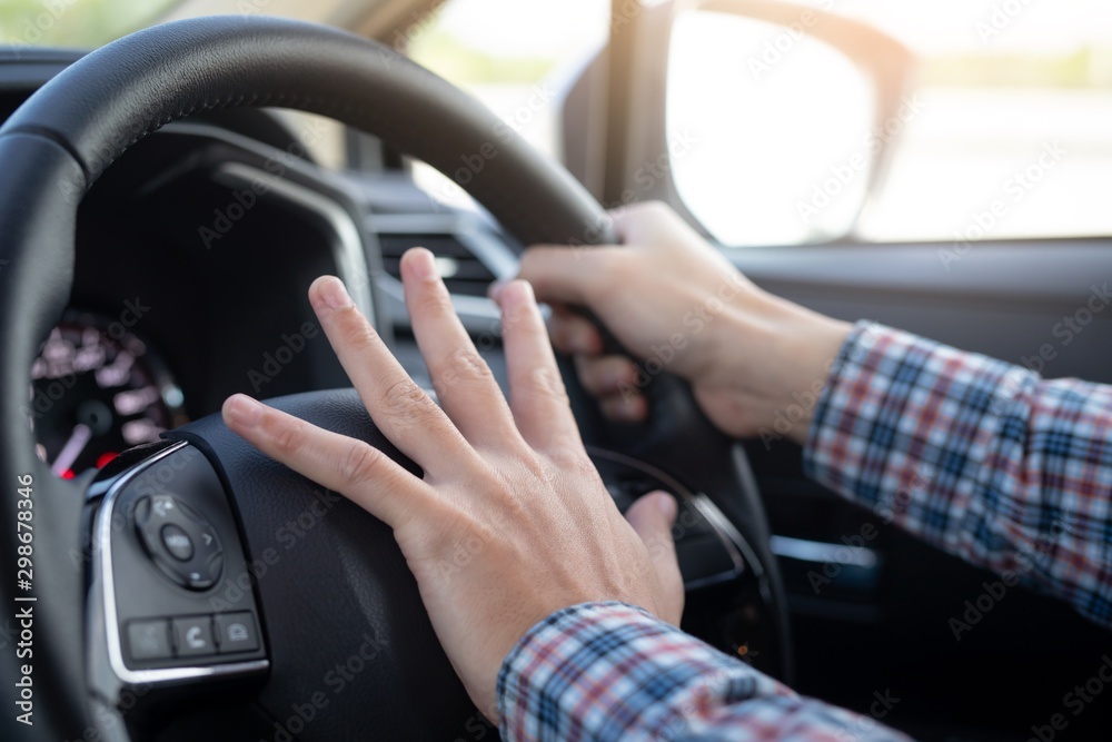 hand on steering wheel of car and honking