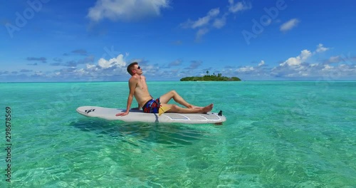 handsome young man resting on the floating paddleboard, maldives,tropical luxury vacation and watersports photo