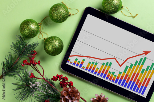 A tablet with a business graph on the desktop. Christmas decorations.