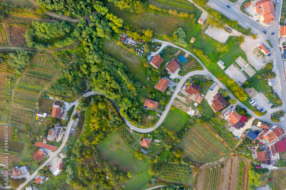 Fototapeta premium Aerial photography of mountainous terrain with the image of vineyards on the slope, winding roads and wooded areas. The view from the top. Shooting from a drone.