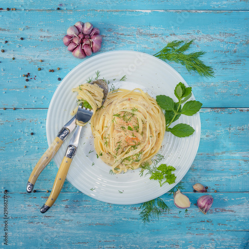 Photos Dish standing on blue wooden table, plate with Italian pasta and chicken with a sauce