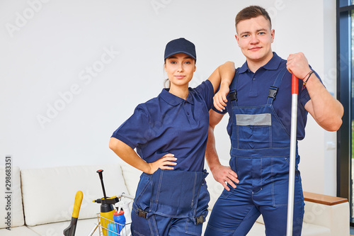 Bilde på lerret Two young members of cleaning service busy with house cleaning session, stand closely against white living room background