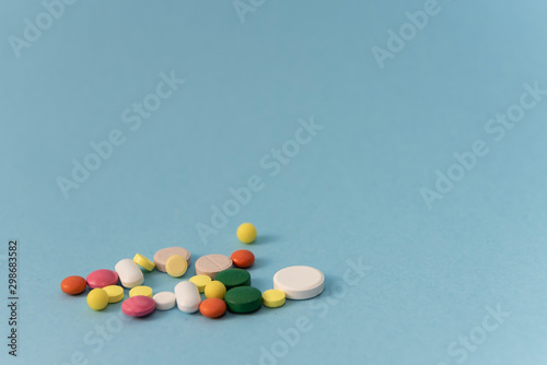 Multicolor tablets on blue background close up. Painkillers, healthcare, treatment pills and drug abuse concept. side view. Copy Space