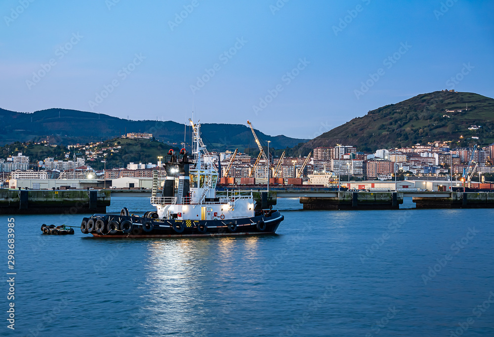 Tugboat with cranes and houses in the background