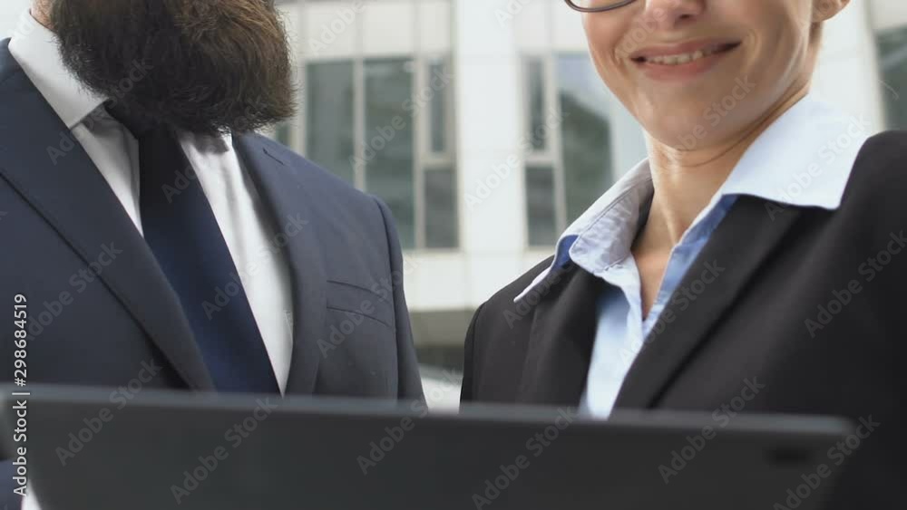 Colleagues with tablet in hands communicating about work project and smiling
