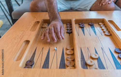 Male playing a traditional oriental board game of backgammon. Close-up men's hands throwing dice photo