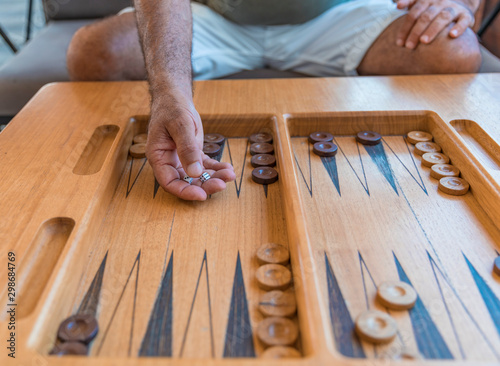 A man playing a traditional oriental board game of backgammon. Men's hands throwing dice photo