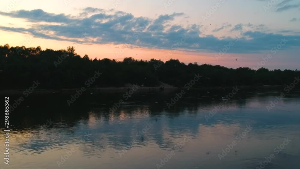 A huge flock of seagulls flies over the river at summer sunset A huge flock of seagulls flies over the river at summer sunset
