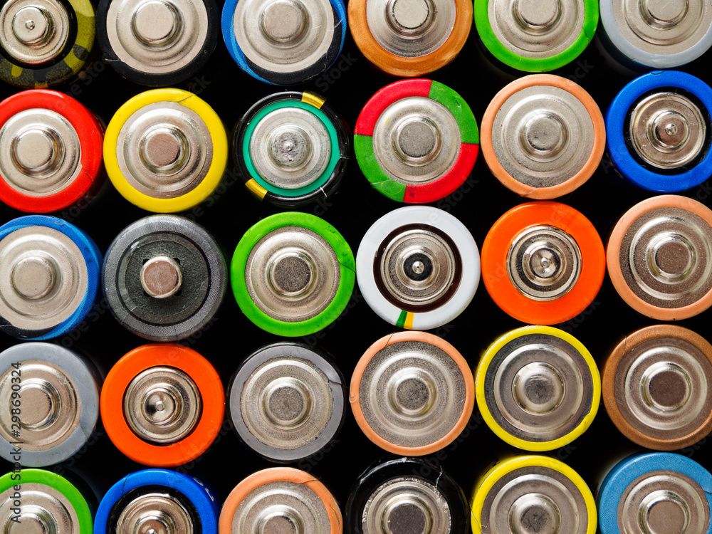 A large number of old AA batteries of different colors. Top view of alkaline batteries. A large number of old AA batteries of different colors. Top view of alkaline batteries.