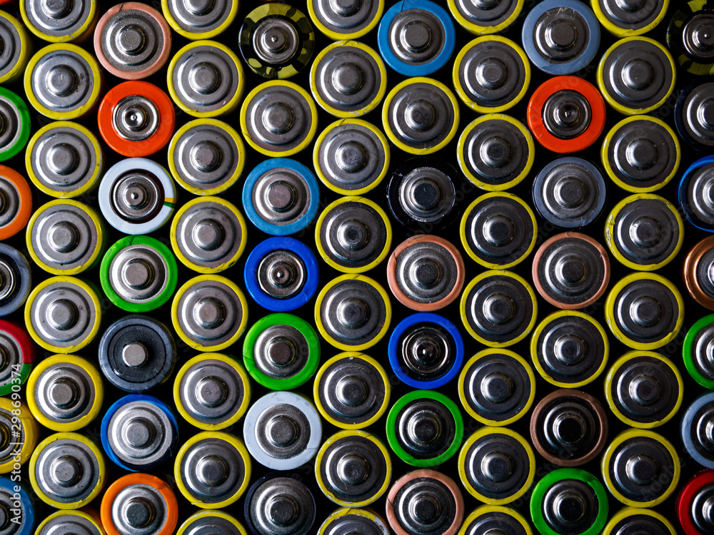 A large number of old AA batteries of different colors. Top view of alkaline batteries. A large number of old AA batteries of different colors. Top view of alkaline batteries.