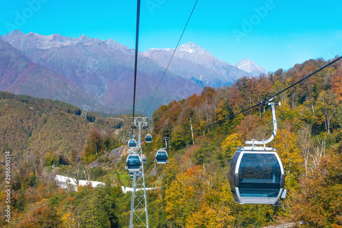 Cableway with ski lifts and cabins for tourists, a view of the town and the autumn forest in the mountains.