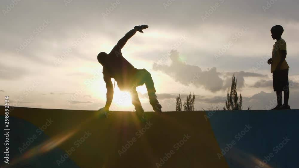 silhouette of a man jumping on the ramp in the skatepark with rollerblades