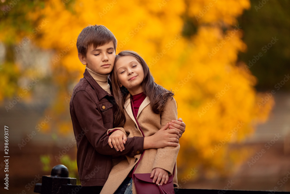 Fototapeta premium Loving boy and girl on a walk in the autumn park, sitting with their eyes closed and dreaming of something.