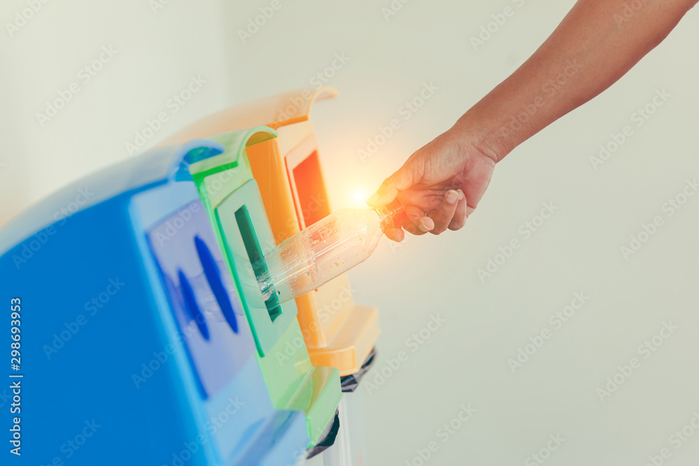 Closeup woman hand throwing empty plastic water bottle into to recycling bin Closeup woman hand throwing empty plastic water bottle into to recycling bin