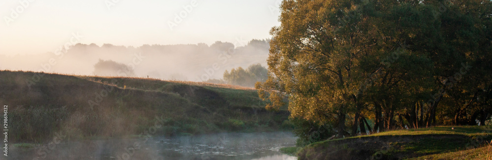 Don river at dawn in the Tula region of Russia. Trees by the river in the morning sun. Reed thickets near the water in the morning fog.