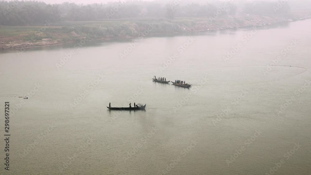 group of fishers in small fishing boats pulling a large net out of river in heavy fog group of fishers in small fishing boats pulling a large net out of river in heavy fog