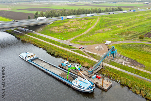 Aerial from freighter unloading sand with the highway A1 in the background in the countryside from the Netherlands
