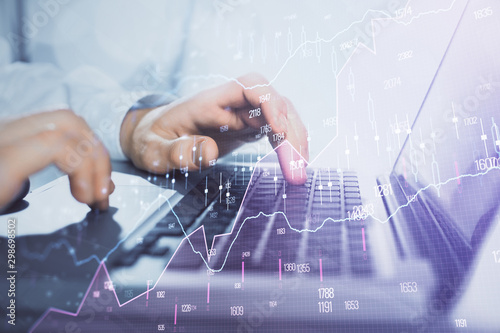 Double exposure of market chart with man working on computer on background. Concept of financial analysis.