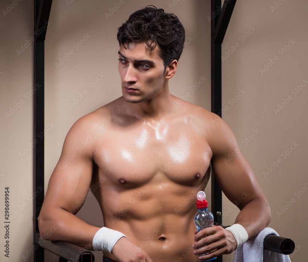 Naklejka premium Thirsty man drinking water in sports gym
