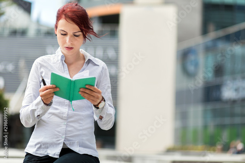 Young secretary reading her agenda outdoor © Minerva Studio