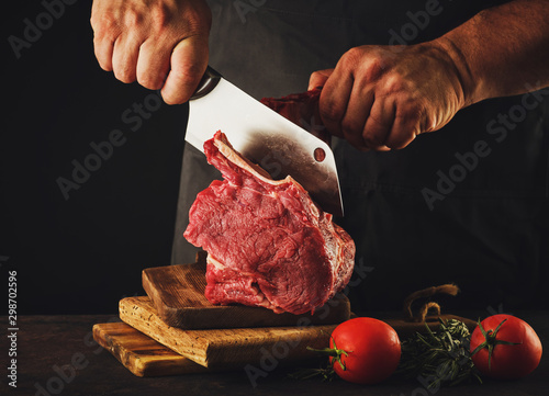 Male butcher cuts raw beef meat.
