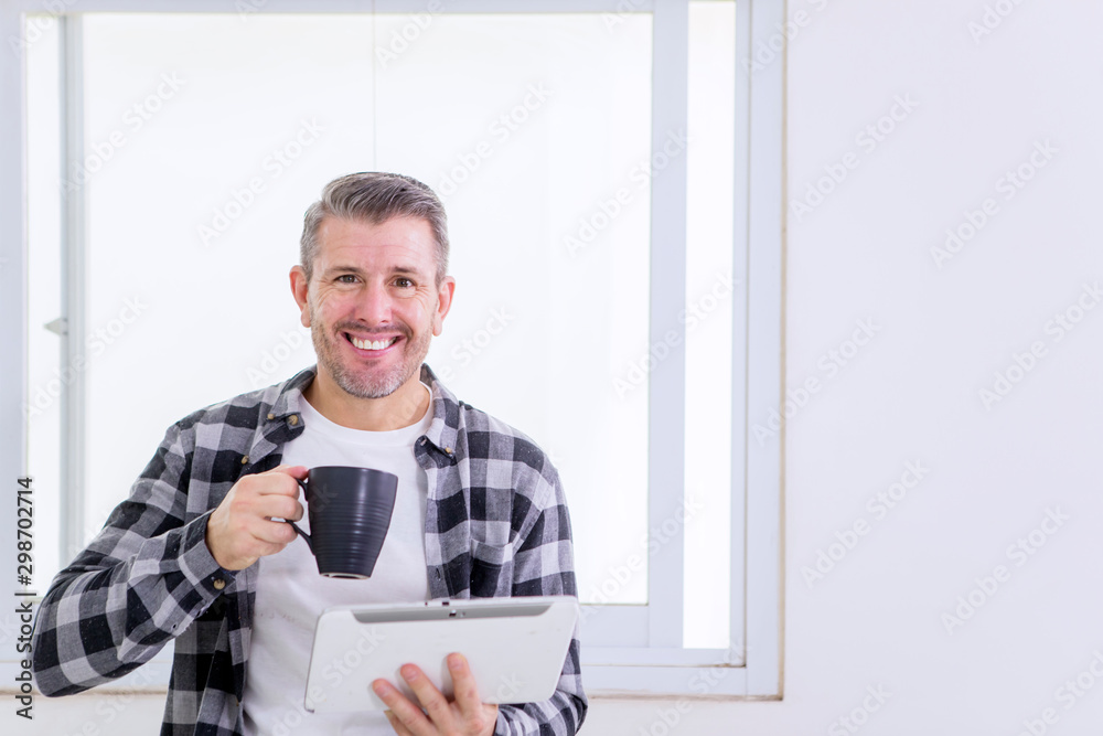 Smiling man holding a cup of coffee and tablet