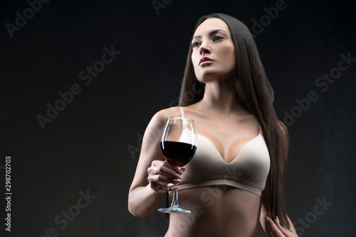 Seductive beautiful woman, perfect figure fit, bra, red wine glass in hand, sraight hair, perfect skin. Copy space