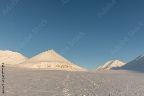 Snowmobile tracks in arctic winter landscape with snow covered mountains on Svalbard  Norway