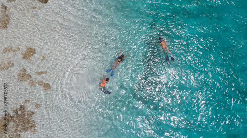 Three young girls snorkeling in blue waters above coral reef  in tropical Caribbean sapphire crystal clear calm waters  People and lifestyle concept