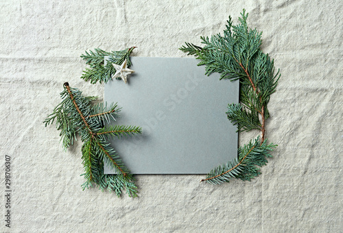 Natural evergreen twigs and a gray paper card for Christmas. Linen background. Flat lay