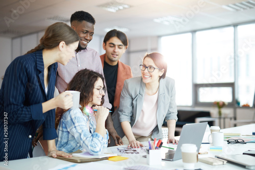 Portrait of multi-ethnic business team smiling cheerfully while discussing creative project during meeting in sunlit office, copy space