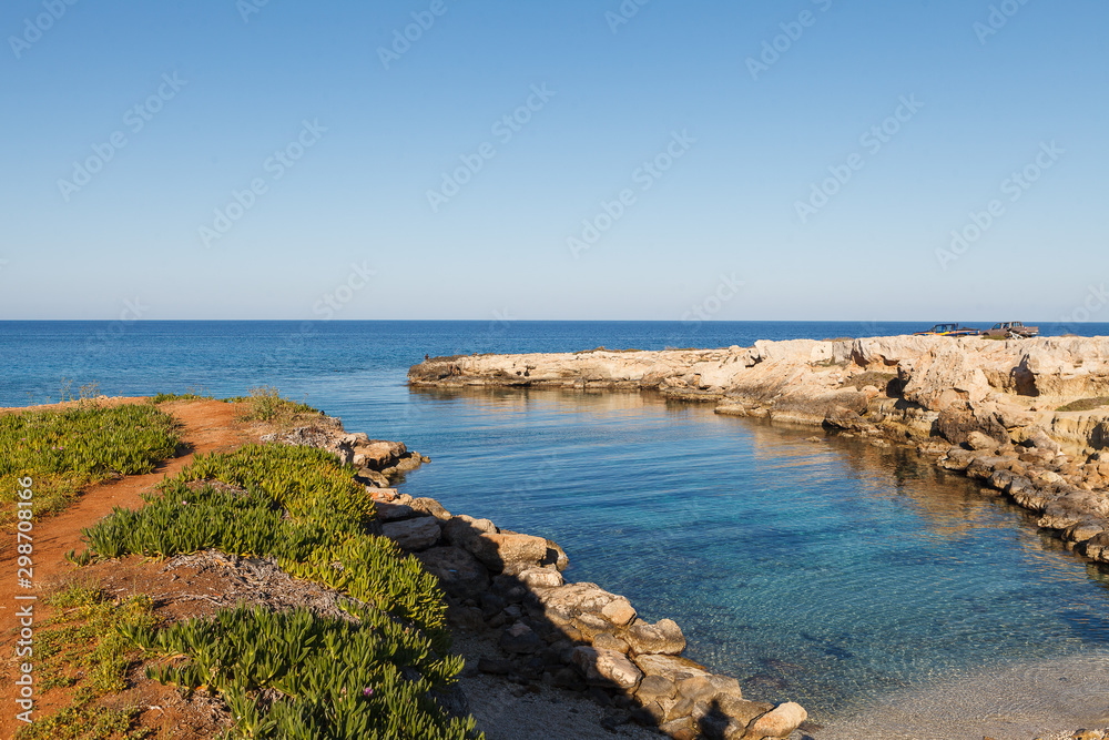 Small remote rocky bay in Cyprus. People enjoy azure sea.