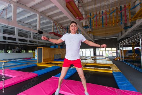 Fitness, fun, leisure and sport activity concept - Handsome happy man jumping on a trampoline indoors