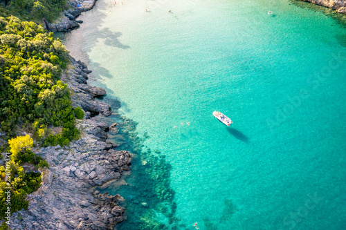 Fototapeta Naklejka Na Ścianę i Meble -  Aerial view of Trsteno beach in Montenegro, near Budva, a boat in a beautiful bay with a rocky shore, blue water, people bathe in clear water