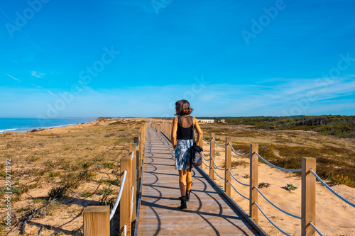 Labenne Océan, les Landes / France »; October 26, 2019: A young man in black and skirt walking along the promenade of the dunes at Labenne Océan beach