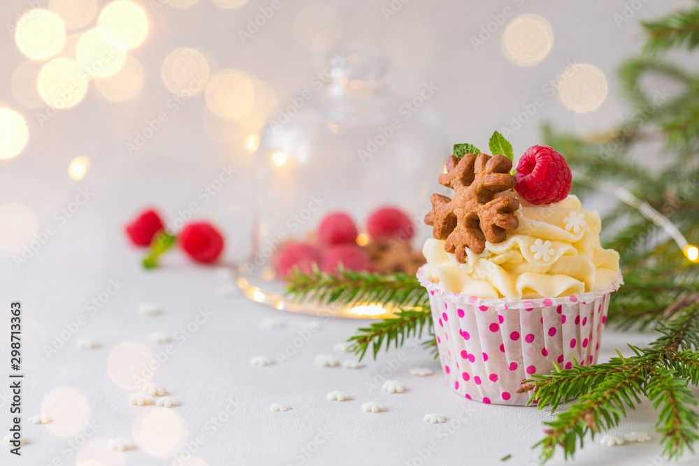 Christmas cupcakes or muffins with cream and raspberry, over the fir tree branches background Christmas cupcakes or muffins with cream and raspberry, over the fir tree branches background