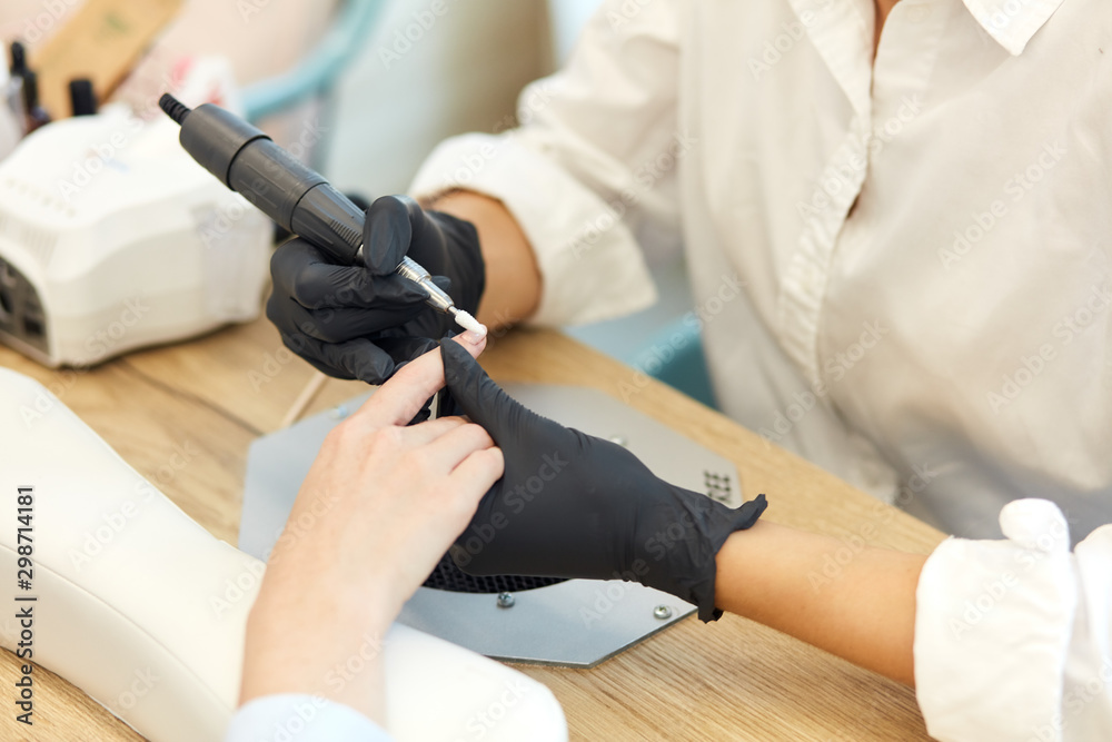 Careful manicurist in black gloves do mechanical manicure of nails. Closeup of beautiful hands. clean and sterile