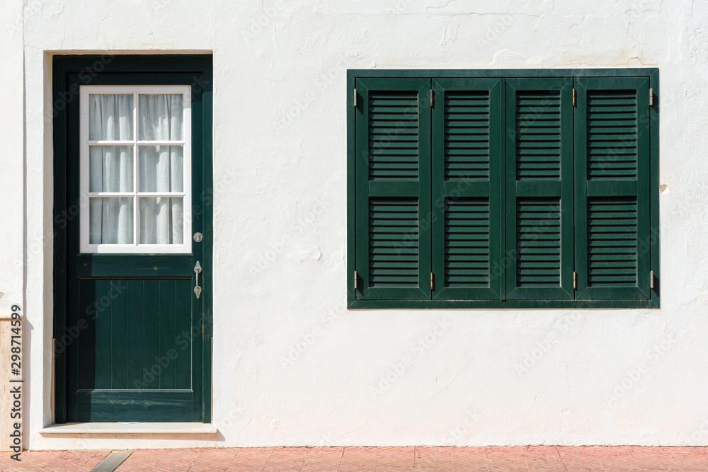 Fototapeta premium Traditional Spanish architecture with white facade and green doors and windows. Menorca, Spain
