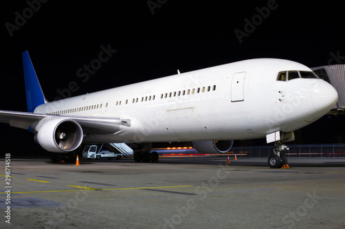 Big modern white aircraft on the parking area in the airport at night, front view © nimdamer