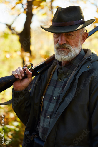Senior caucasian man holding shotgun.Sad, serious after hunting in forest © alfa27