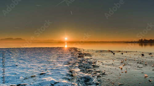 Panorama of beautiful sunset in Chieming. Ice in front of sunset. Chiemsee