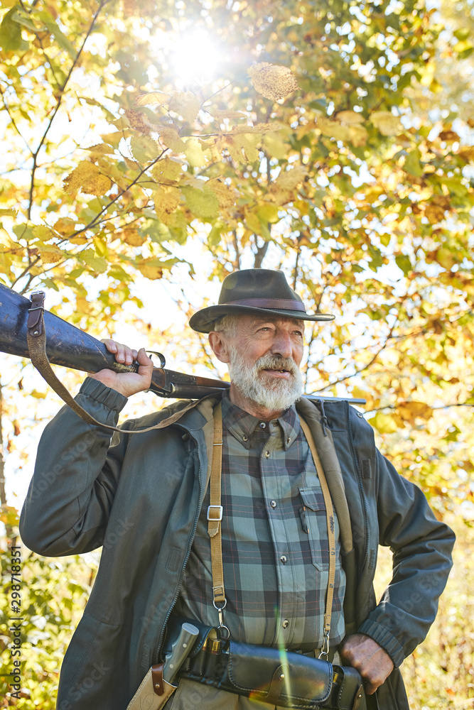 Older hunter spend leisure hunting. Brutal bearded man in hat, nature background.