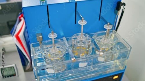 Experiments at the lab. Sliding shot of a dissolution apparatus testing medication pills dissolving tablets in liquid. Laboratory routine.