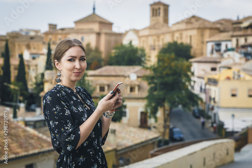 Pretty young woman in a black dress using smartphone at old town street. Travel by Europe. Toledo, Spain