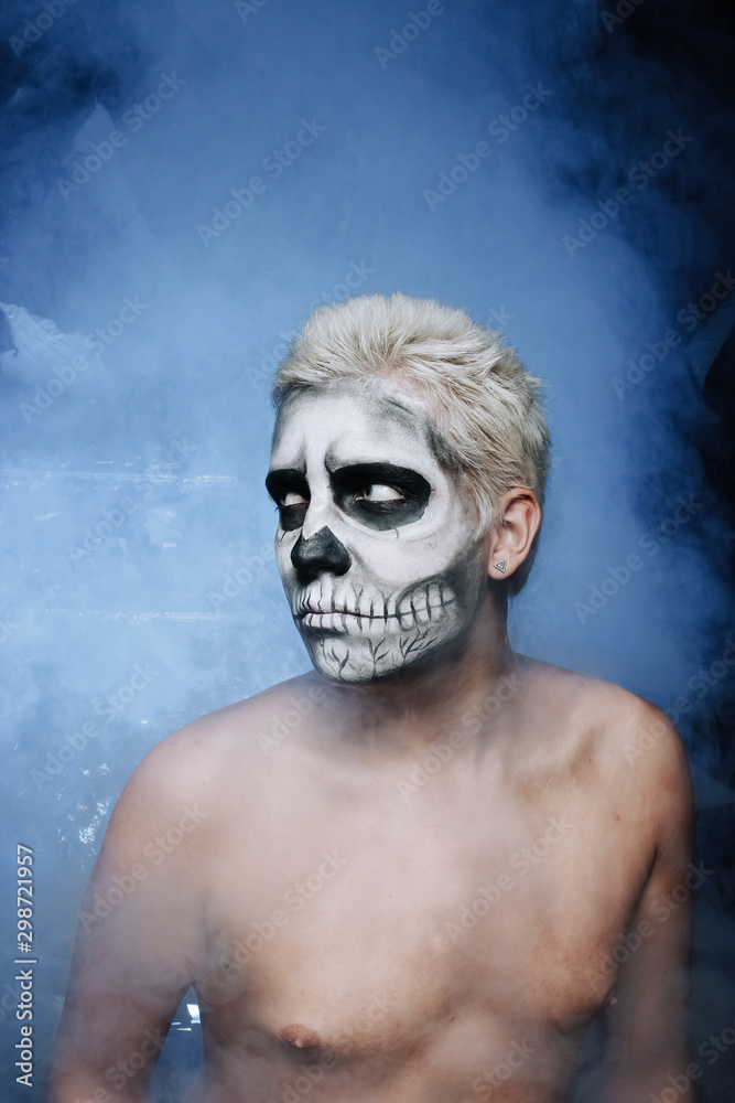 portrait of a man with halloween face art make up alone in the dark background