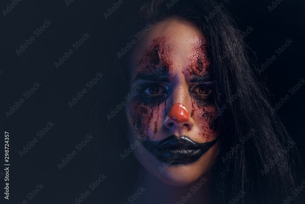 Portrait of spooky evil joker with scary makeup at dark photo studio. Portrait of spooky evil joker with scary makeup at dark photo studio.