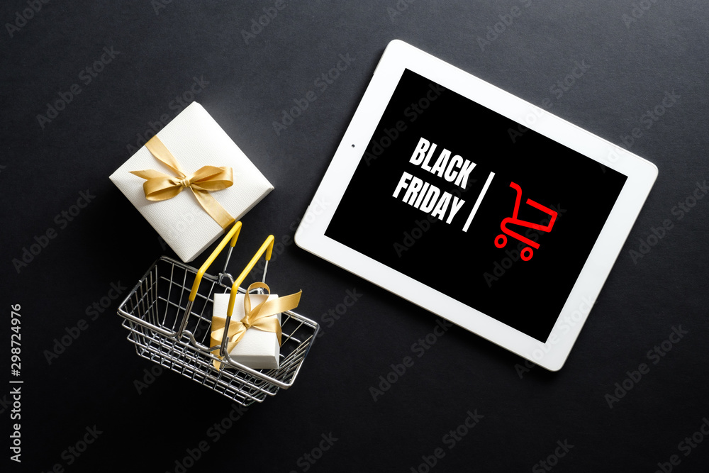 Black Friday sale concept. Tablet pad with sign "Black Friday" on screen,  shopping basket, gift box over black background. Flat lay, top view,  overhead. Stock Photo | Adobe Stock