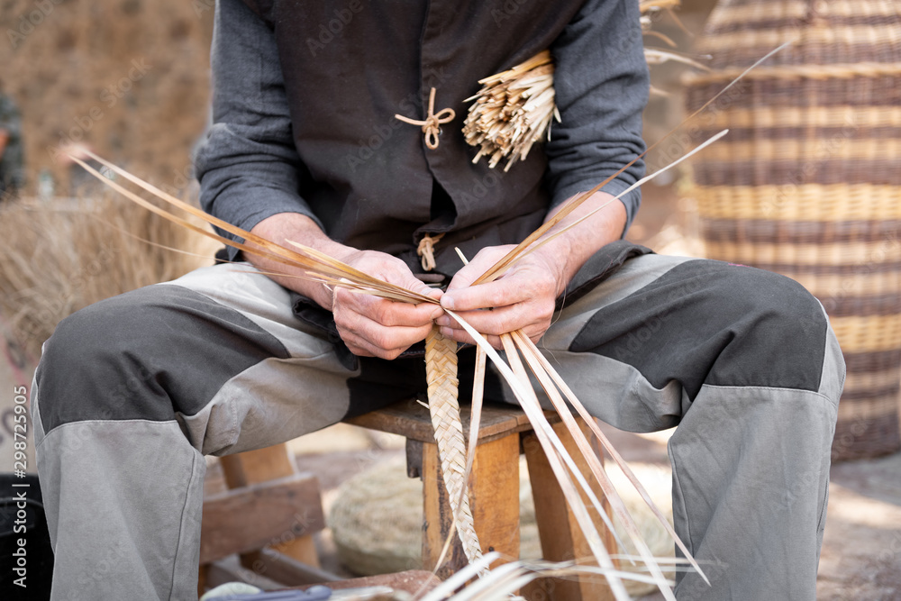 old wicker craftsman with hands working in isolated foreground. - obrazy, fototapety, plakaty 