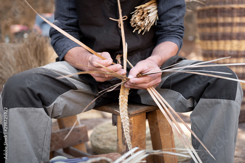 old wicker craftsman with hands working in isolated foreground.