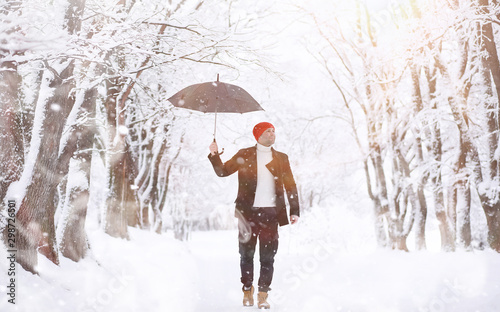 A man on a walk in the park. Young man with in the winter snowfall.